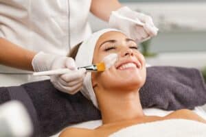 Woman smiling as she gets a facial treatment in a spa setting